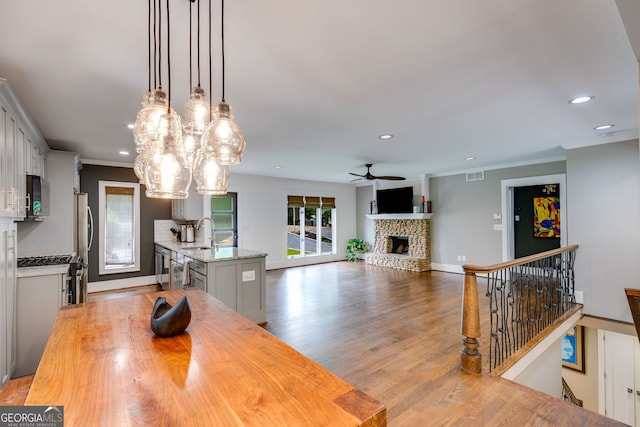 921 Oak Dr, Woodstock, GA 30189 - dining area featuring a fireplace with raised hearth, recessed lighting, ceiling fan, crown molding, and light wood-style flooring