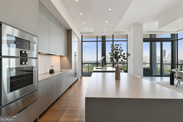 3107 Peachtree Rd NE Unit 2003Aka Ph3, Atlanta, GA 30305 - kitchen featuring modern cabinets, double oven, floor to ceiling windows, gray cabinets, and wood finished floors