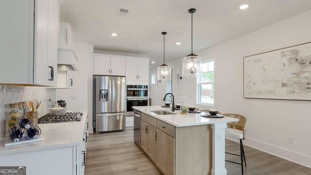 kitchen with stainless steel appliances, a sink, light countertops, light wood finished floors, and recessed lighting