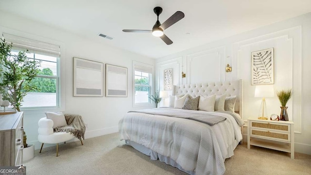 bedroom with multiple windows, light colored carpet, and baseboards