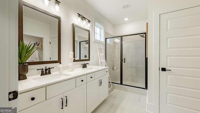 bathroom featuring a shower stall and double vanity