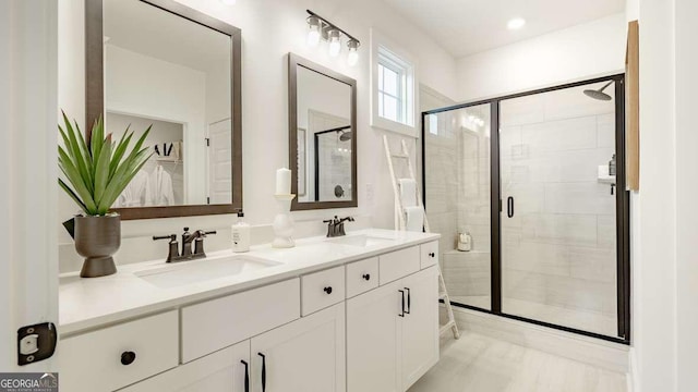bathroom with a stall shower, double vanity, and a spacious closet