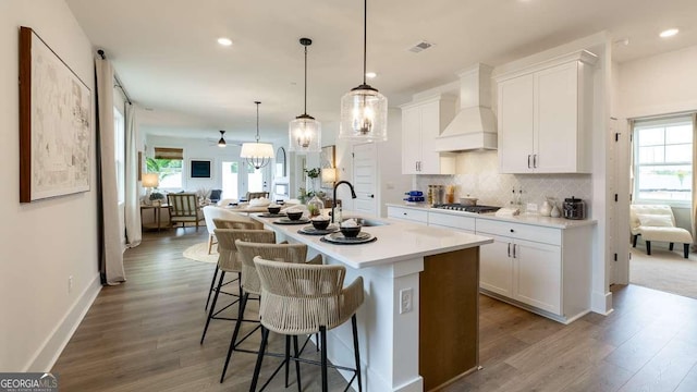 kitchen with custom exhaust hood, a sink, wood finished floors, gas stovetop, and open floor plan