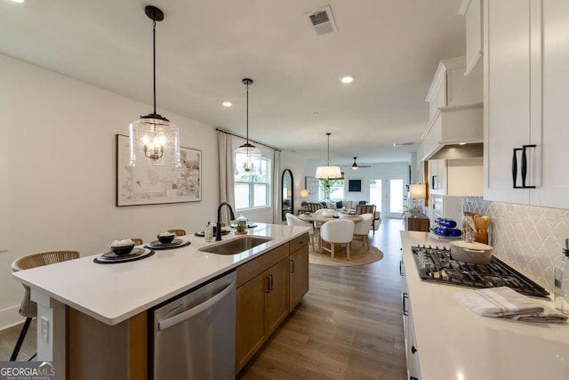 kitchen featuring a sink, dishwasher, open floor plan, light countertops, and backsplash