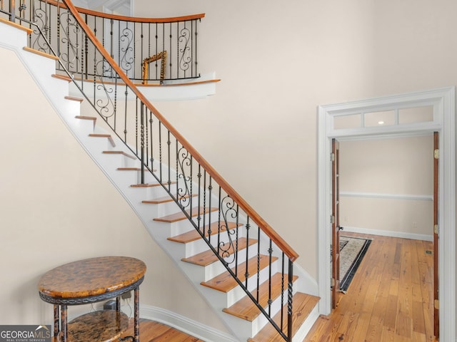 stairs with baseboards, hardwood / wood-style flooring, and a high ceiling
