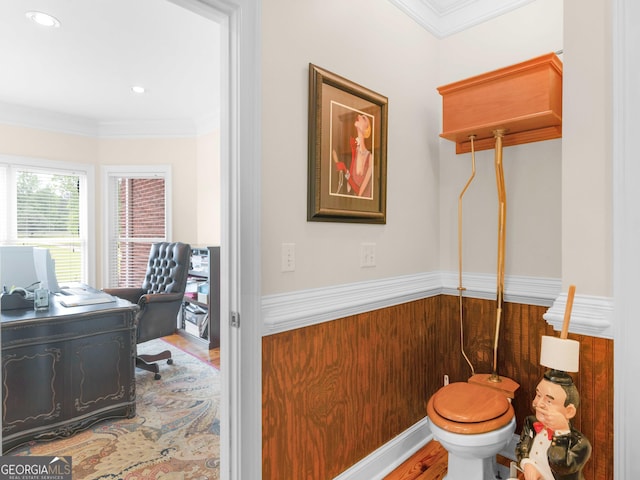 bathroom with ornamental molding, toilet, wood finished floors, and a wainscoted wall