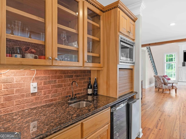 kitchen with a sink, wine cooler, crown molding, backsplash, and light wood-style flooring