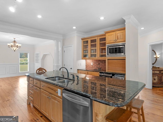 kitchen with appliances with stainless steel finishes, a sink, a center island with sink, a breakfast bar, and crown molding
