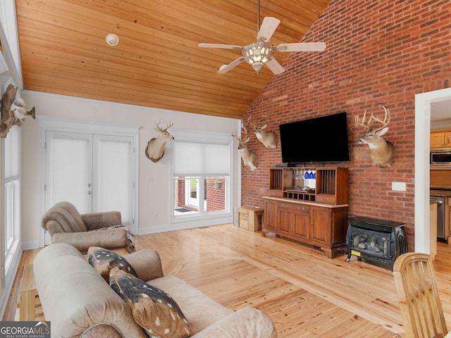 living room featuring a wood stove, wood ceiling, a ceiling fan, high vaulted ceiling, and brick wall