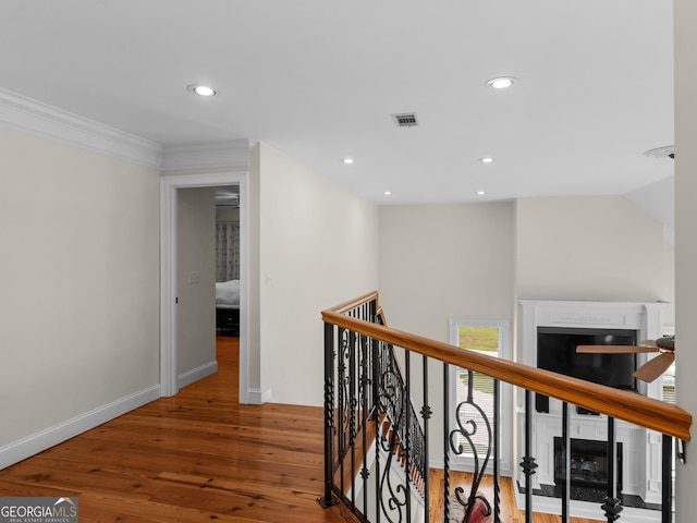hallway featuring wood-type flooring, recessed lighting, an upstairs landing, baseboards, and crown molding