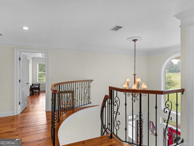 hall with an upstairs landing, a chandelier, ornamental molding, wood finished floors, and baseboards