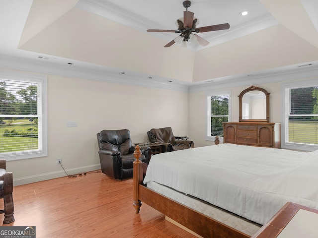 bedroom with a tray ceiling, ornamental molding, recessed lighting, multiple windows, and light wood-style floors
