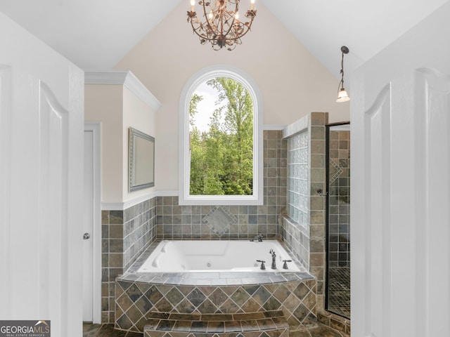 bathroom with a jetted tub, lofted ceiling, a chandelier, and a tile shower