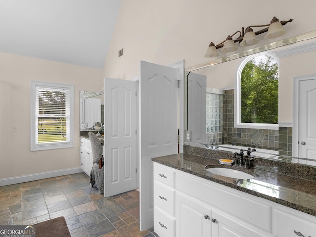 full bathroom featuring vanity, stone tile floors, baseboards, and high vaulted ceiling