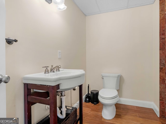 half bathroom featuring toilet, wood finished floors, and baseboards
