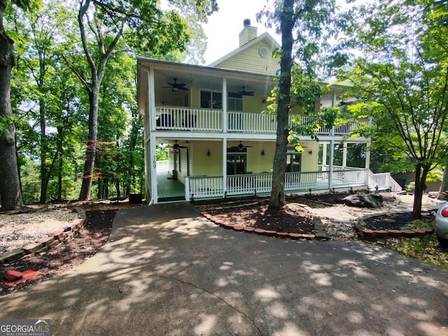 view of front of property with a ceiling fan, a porch, a chimney, and a balcony