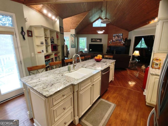 kitchen with cream cabinetry, dishwasher, a sink, vaulted ceiling, and wood ceiling