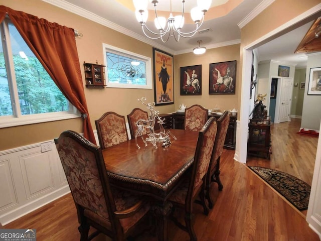 dining area with a chandelier, wood finished floors, and crown molding