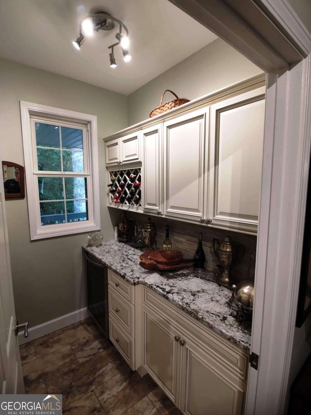 indoor dry bar featuring dishwasher, backsplash, and baseboards