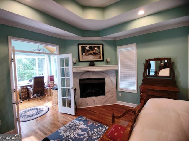 bedroom featuring an office area, wood finished floors, a premium fireplace, french doors, and ornamental molding