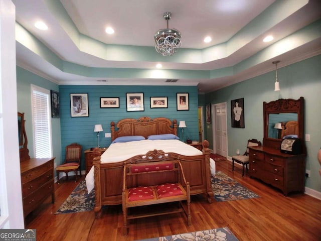 bedroom with a tray ceiling, baseboards, wood finished floors, recessed lighting, and crown molding