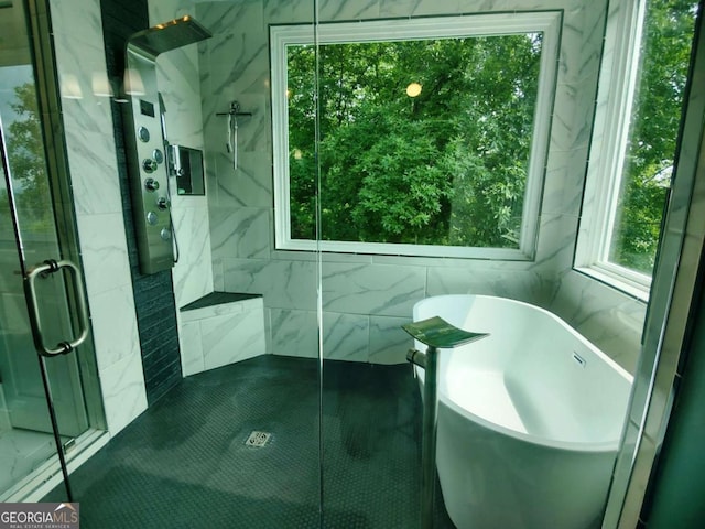 bathroom with a marble finish shower, tile walls, and a freestanding tub
