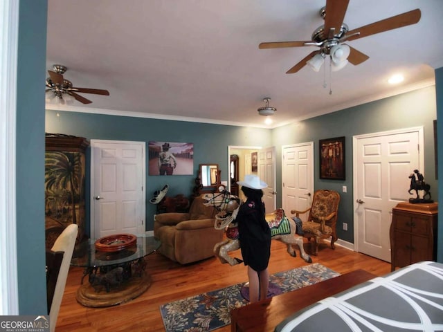 bedroom with wood finished floors, ceiling fan, ornamental molding, and baseboards