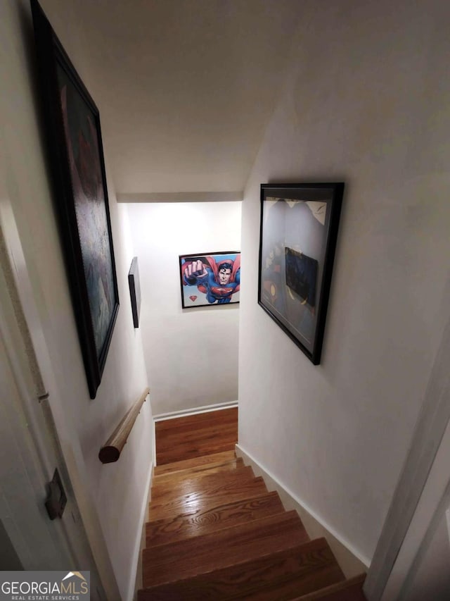staircase featuring wood finished floors and baseboards