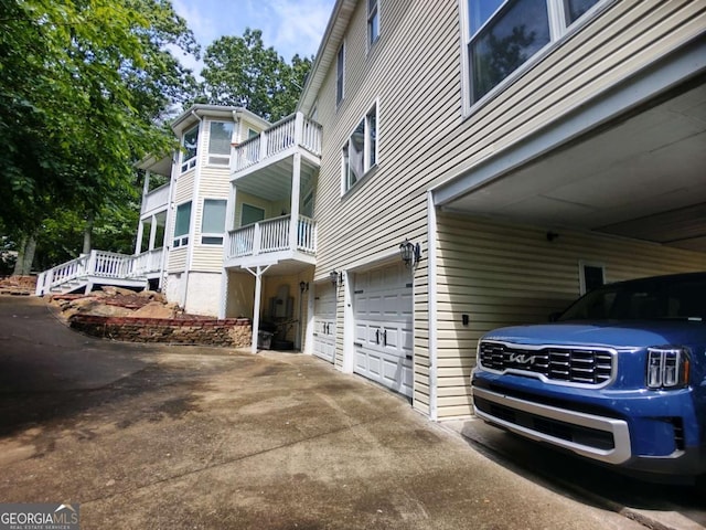 view of side of home with an attached garage, driveway, and a balcony
