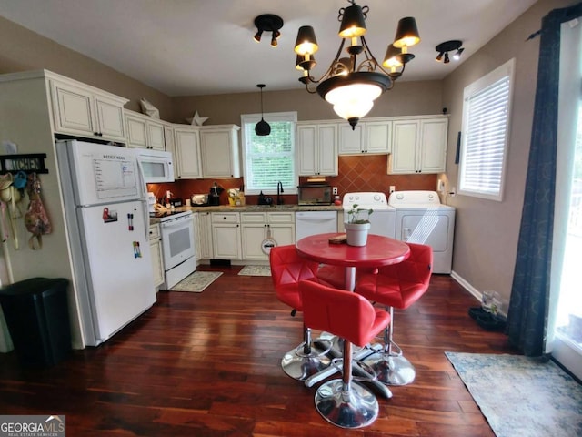 kitchen featuring washing machine and dryer, white appliances, dark wood-style floors, a chandelier, and tasteful backsplash