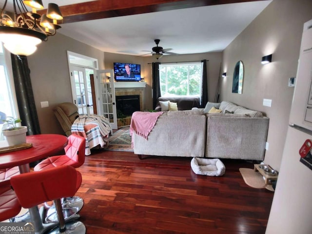 living area featuring dark wood finished floors, ceiling fan, a fireplace, and a chandelier