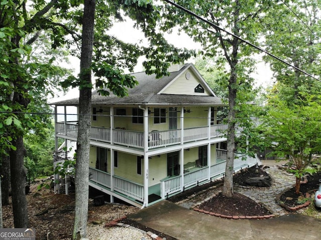 back of house with a balcony, covered porch, and a shingled roof