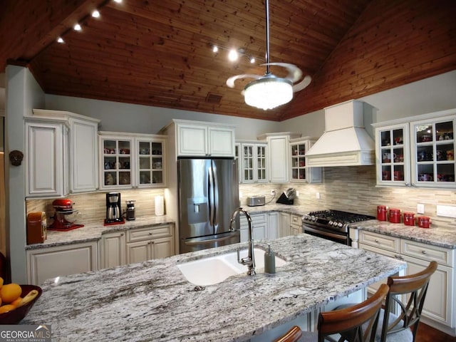 kitchen with premium range hood, stainless steel appliances, a sink, wood ceiling, and tasteful backsplash
