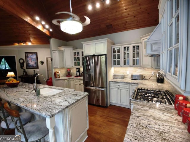 kitchen with stainless steel fridge, a sink, wood ceiling, lofted ceiling, and backsplash