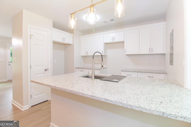 330 Stonehenge Way, Athens, GA 30606 - kitchen with white cabinets, light wood-style flooring, light stone countertops, decorative light fixtures, and a sink