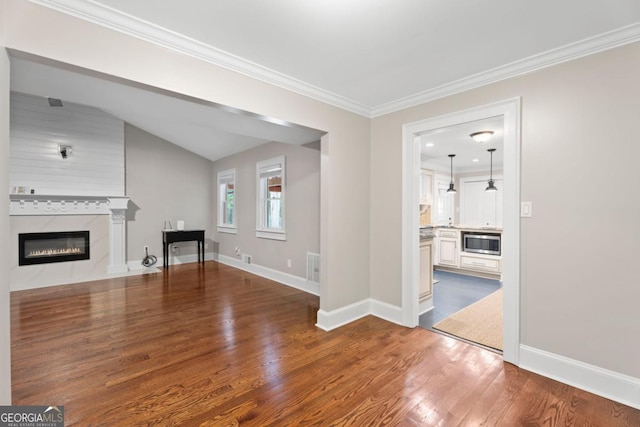 unfurnished living room featuring a fireplace, wood finished floors, baseboards, crown molding, and vaulted ceiling