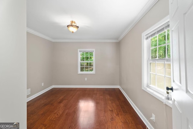 empty room featuring dark wood-style flooring, baseboards, and ornamental molding