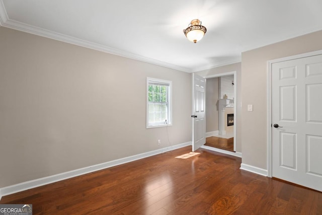 unfurnished bedroom featuring ornamental molding, wood finished floors, baseboards, and a large fireplace
