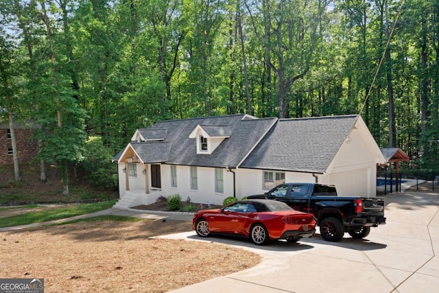 view of front of property with driveway, a garage, and a shingled roof
