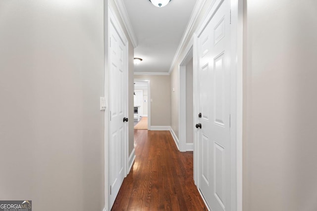 hall with dark wood-style floors, ornamental molding, and baseboards