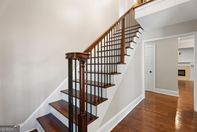 staircase featuring wood finished floors and baseboards