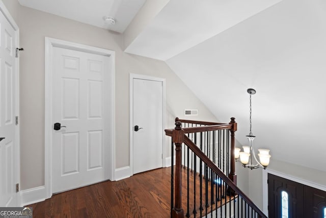 hall featuring an upstairs landing, dark wood finished floors, a chandelier, vaulted ceiling, and baseboards