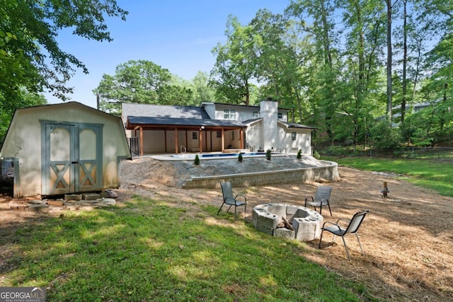 view of grassy yard with a fire pit, a patio, and an outdoor pool