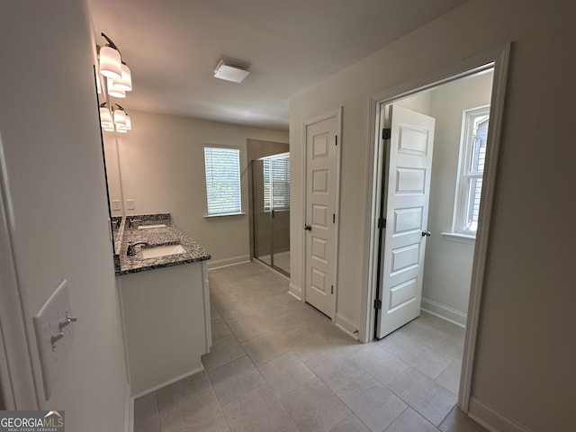 full bath with a stall shower, tile patterned floors, vanity, and baseboards