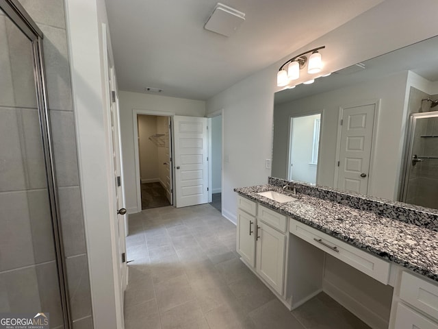 full bath with a stall shower, a spacious closet, vanity, and tile patterned floors