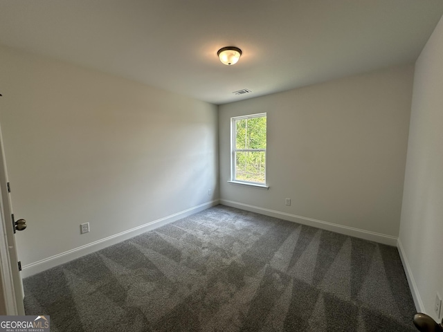 spare room featuring dark carpet and baseboards