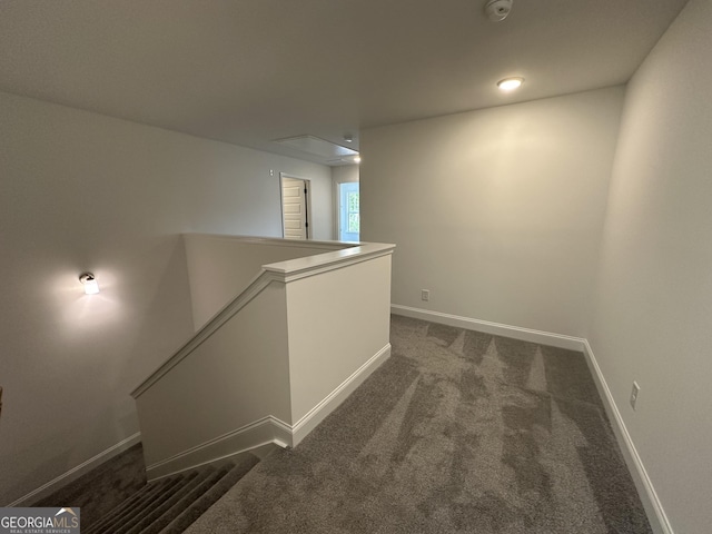 corridor featuring an upstairs landing, dark carpet, attic access, and baseboards