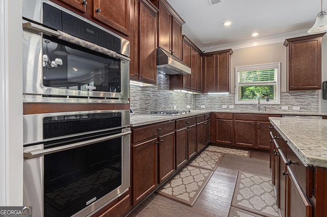 4815 Edgemoore Trce, Cumming, GA 30040 - kitchen featuring under cabinet range hood, appliances with stainless steel finishes, decorative backsplash, crown molding, and light stone counters