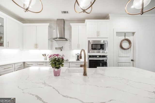 377 Parker Rd, Mcdonough, GA 30252 - kitchen with wall chimney exhaust hood, appliances with stainless steel finishes, white cabinets, glass insert cabinets, and ornamental molding
