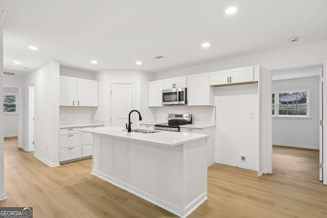 2765 Ocean Valley Dr, Atlanta, GA 30349 - kitchen with appliances with stainless steel finishes, a sink, decorative backsplash, white cabinetry, and a kitchen island with sink